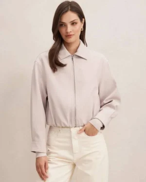 Model wearing an off-white zip-up casual jacket with a collar and white trousers against a neutral background